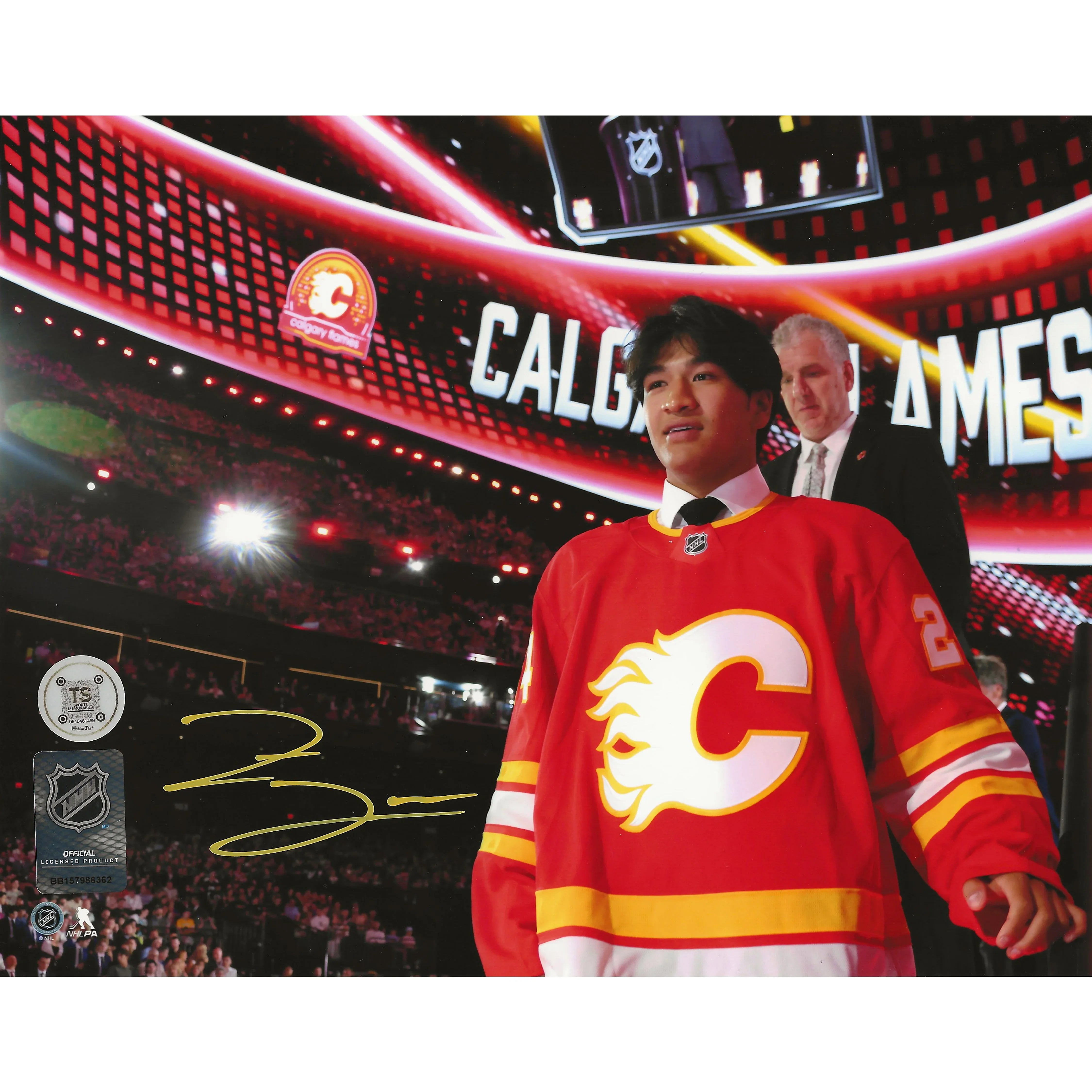 Young man in Calgary Flames jersey at NHL draft event with autograph and crowd in arena