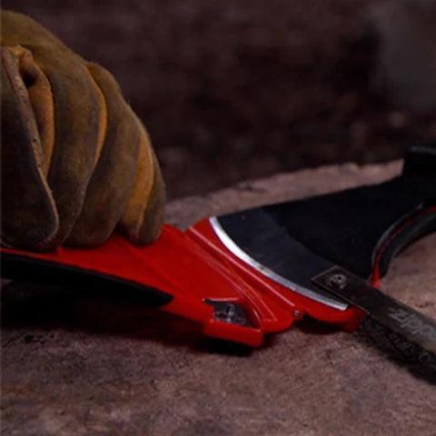 Gloved hand using Zippo AxeSaw on wood outdoors, camping tool close-up