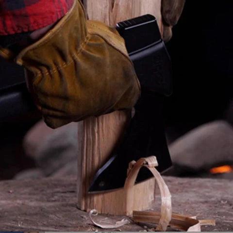 Gloved hand using a Zippo AxeSaw to split wood outdoors on a tree stump.