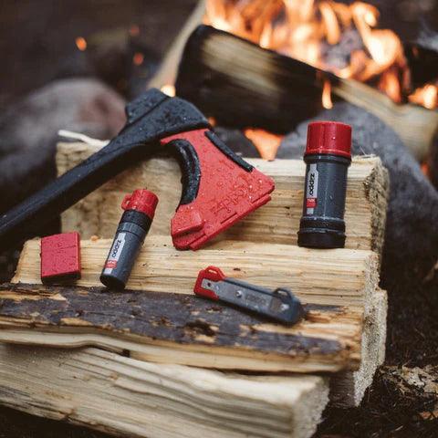 Zippo AxeSaw multitool and Zippo accessories on firewood by a campfire outdoors