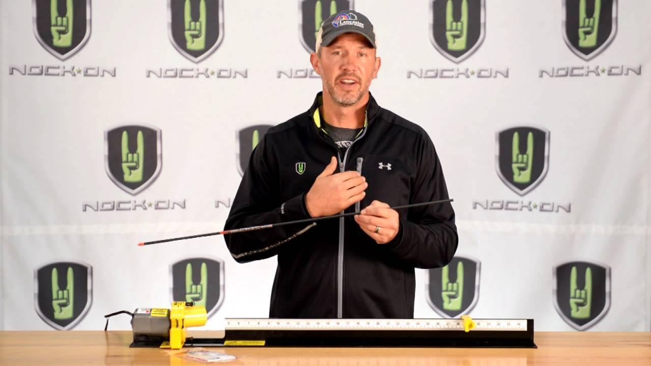 Man demonstrating arrow cutting with arrow saw and Nock On branded backdrop