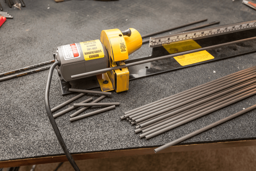 Arrow shafts being cut with a yellow electric cutter on a workbench, carbon arrows