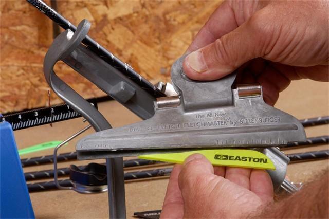 Person using arrow fletching jig to attach Easton vanes for archery arrow repair
