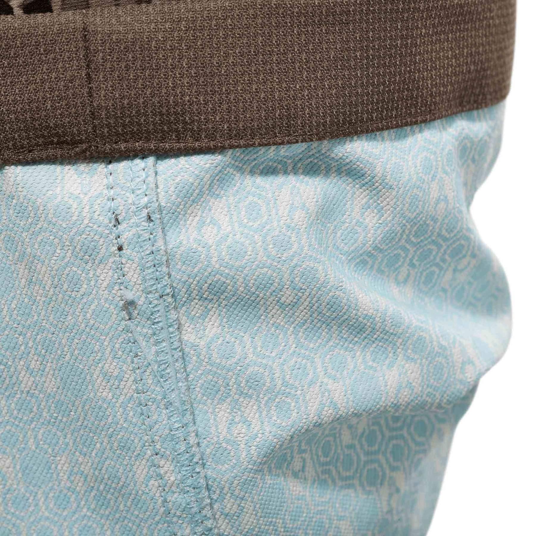 Close-up of Badlands Algus Pant blue fabric with hex pattern and brown waistband