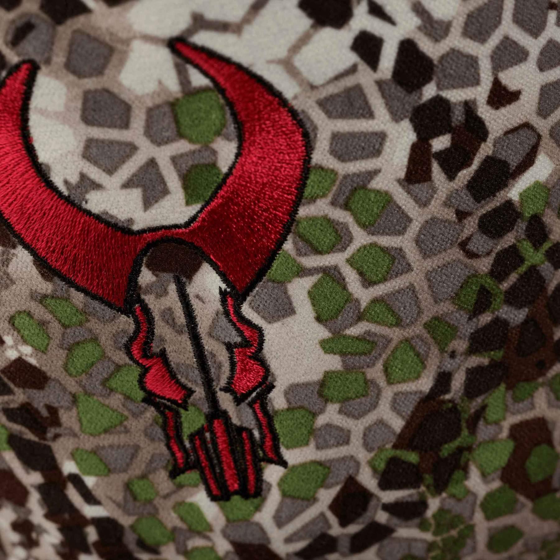 Badlands gaiter closeup with red embroidered logo on camo fabric, outdoor sports gear