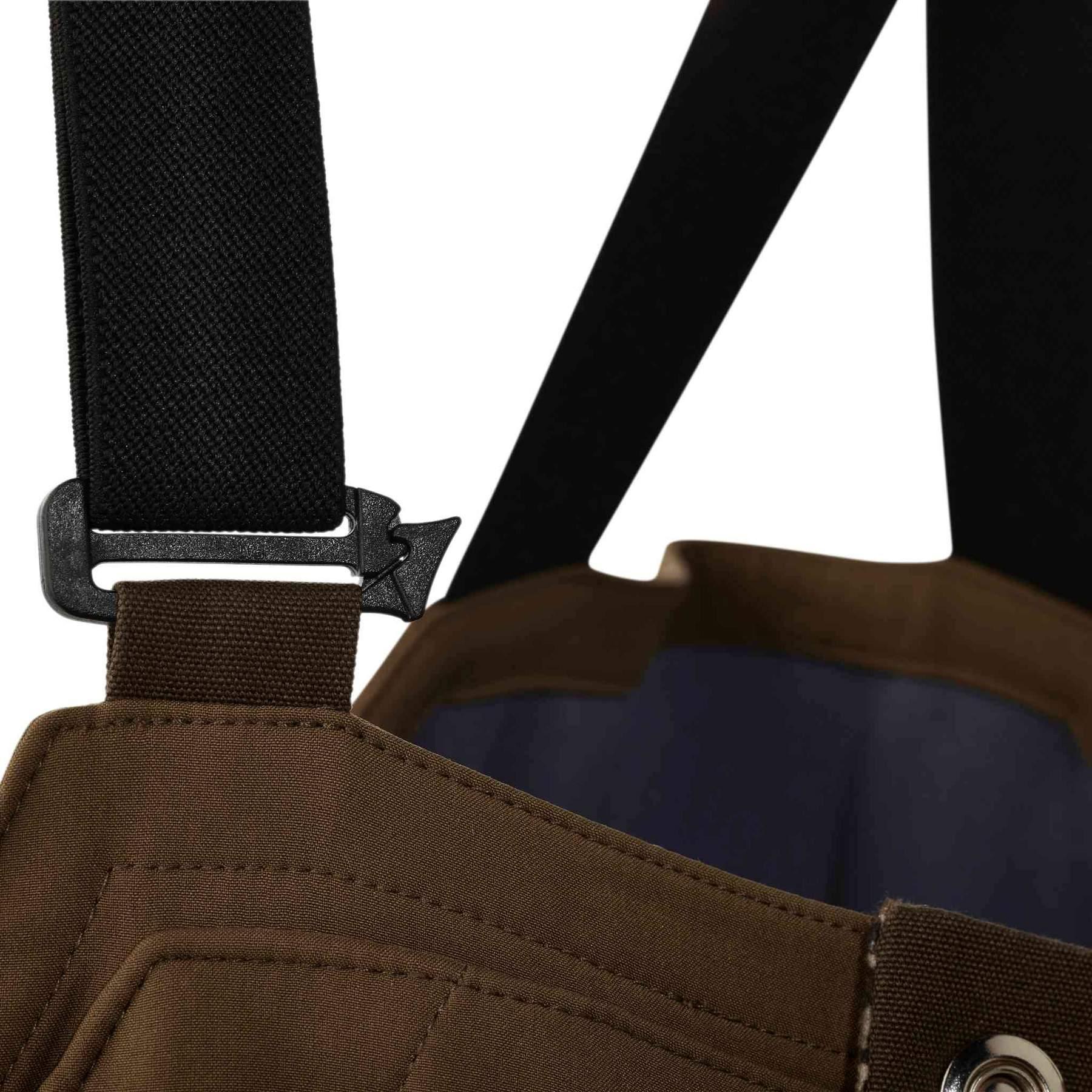 Close-up of brown outdoor bib overalls with black adjustable suspender strap and buckle