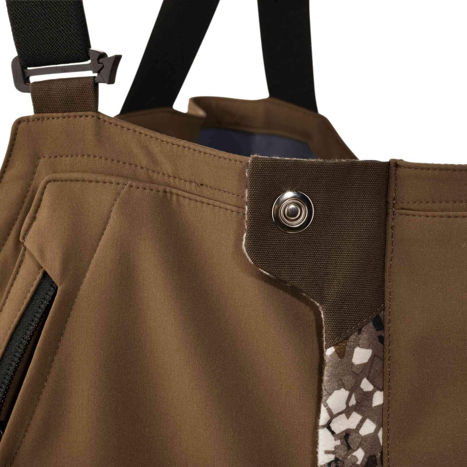 Close-up of Badlands Pyre Bib brown hunting pants with snap closure and camo detail