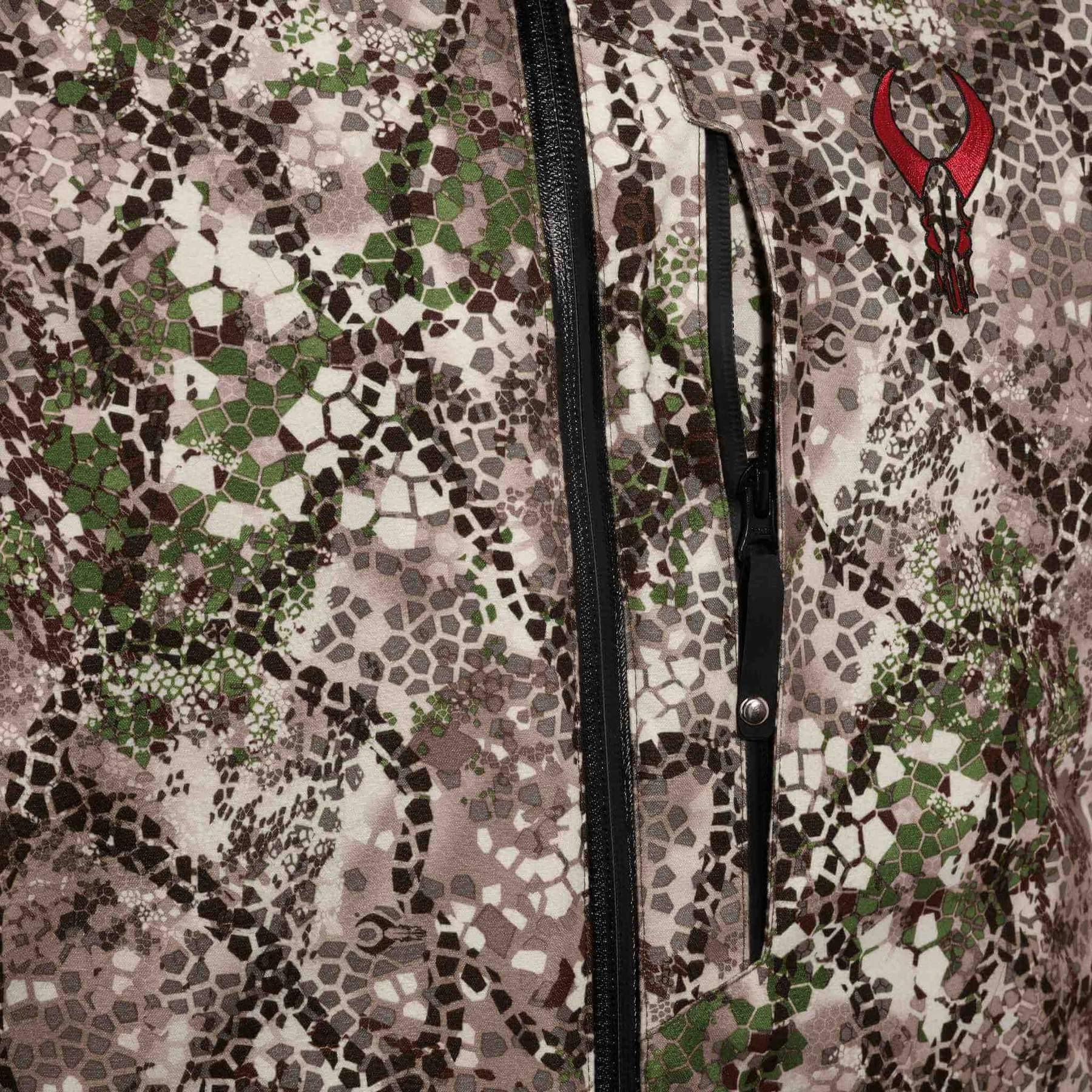 Badlands Pyre Jacket close-up showing camo pattern, chest zipper, and red skull logo.