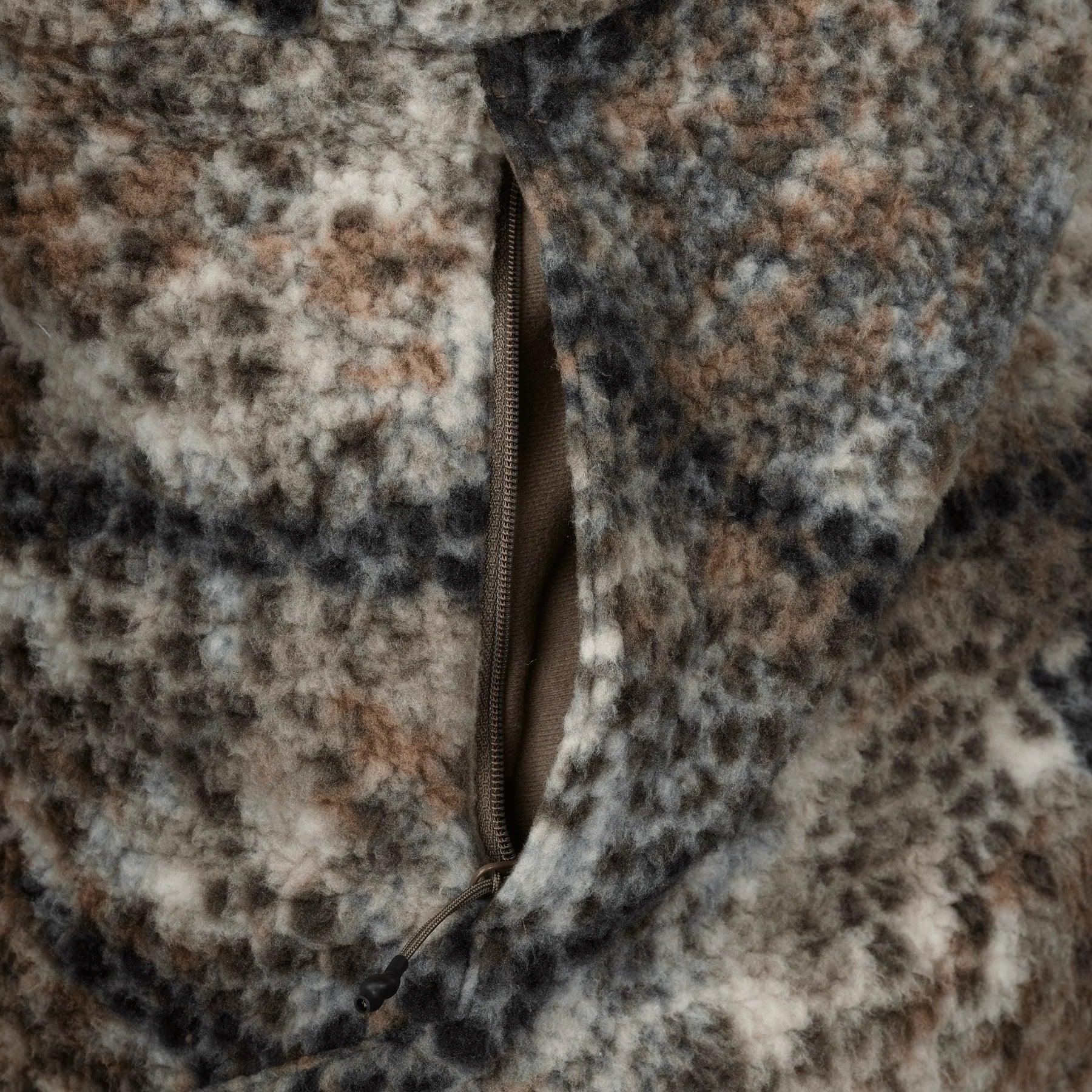 Close-up of camouflage fleece jacket zip pocket with textured outdoor fabric
