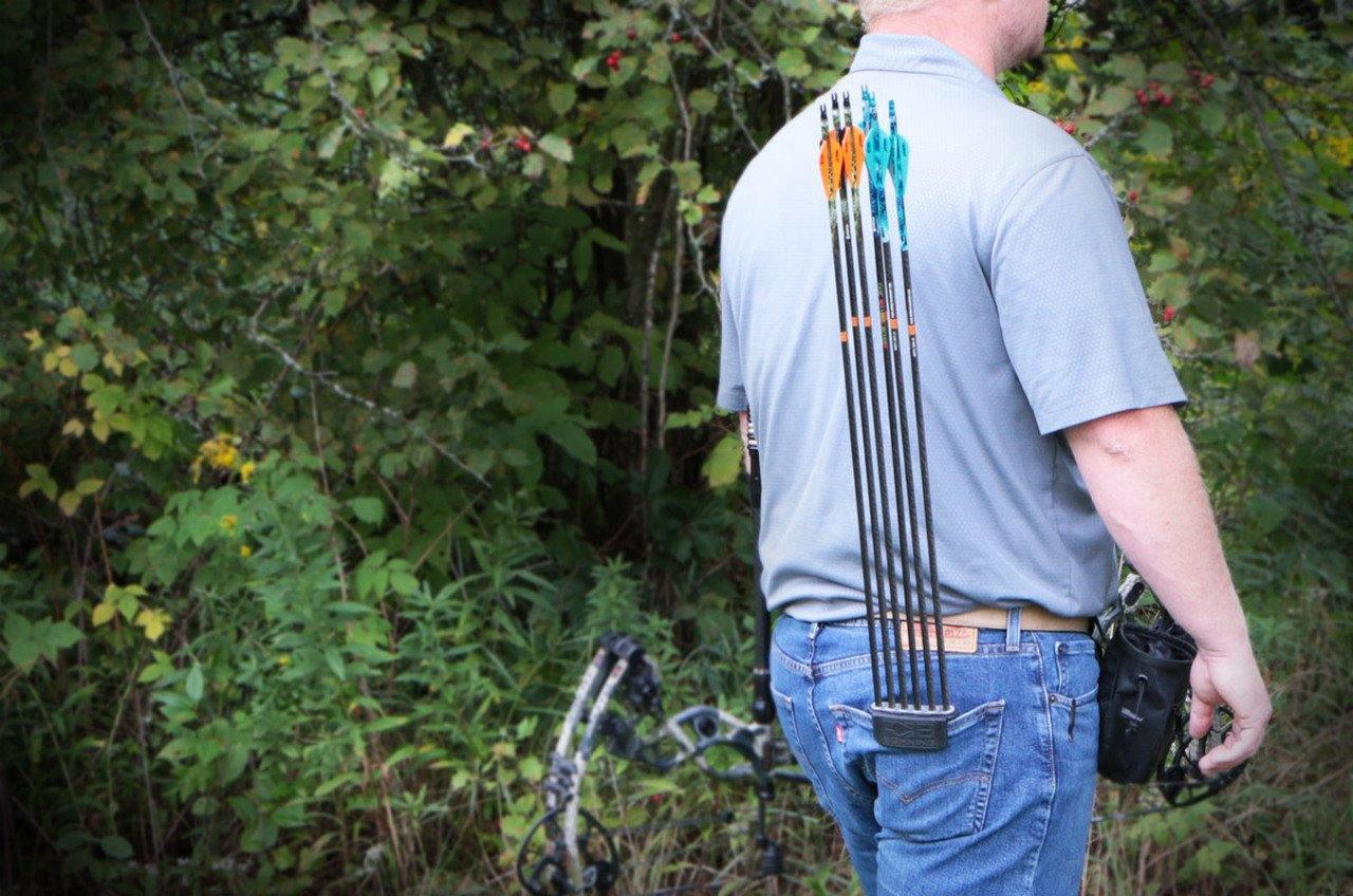 Man wearing Bohning Archery Pocket Quiver with arrows outdoors near forest greenery