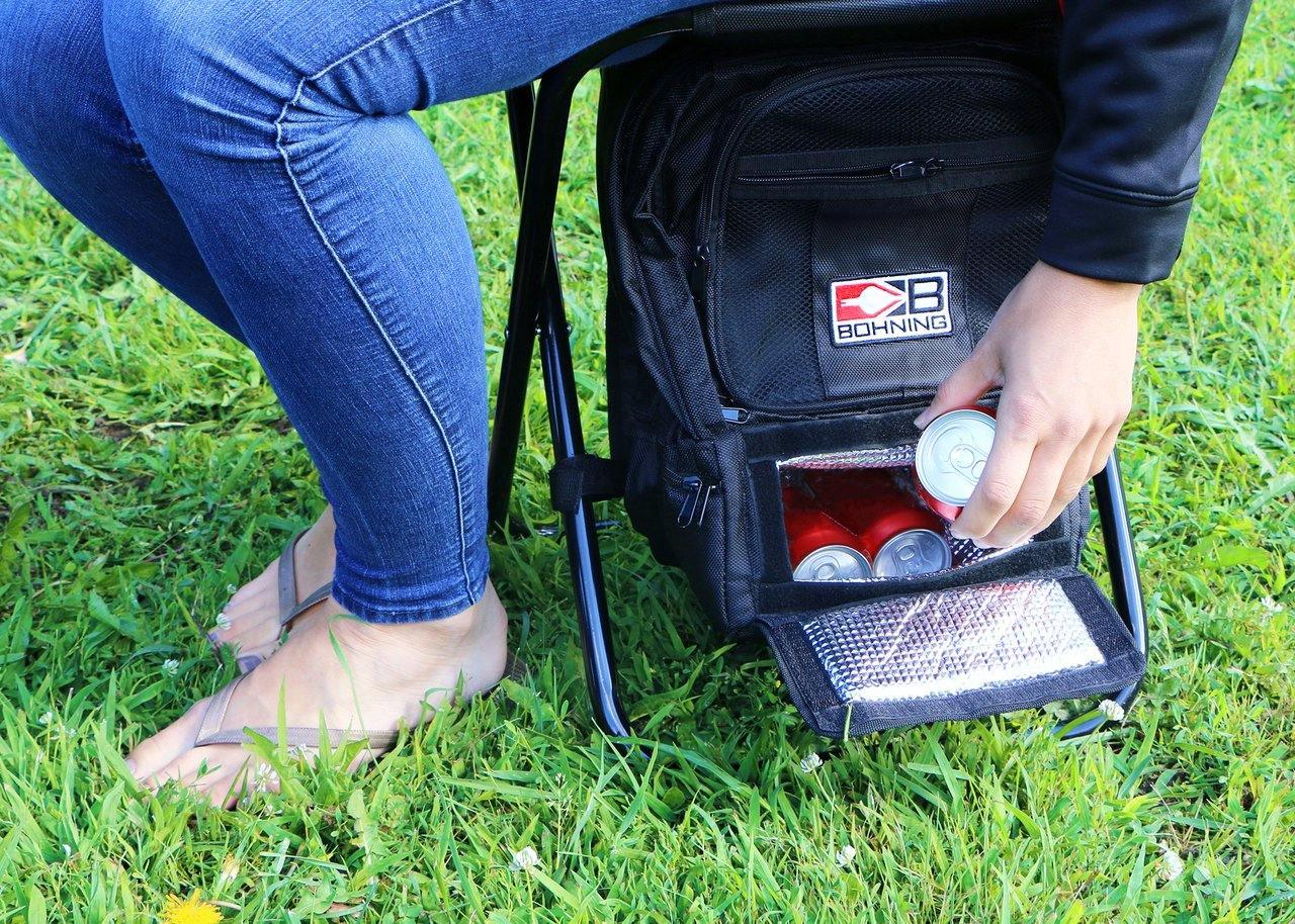 Person sitting on Bohning archery shooter stool with cooler pocket holding soda cans on grass