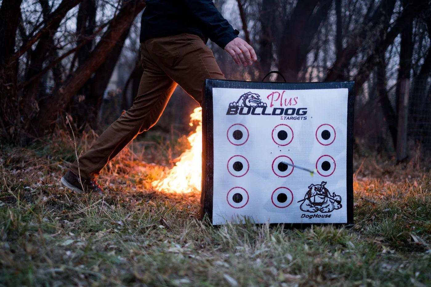 Bulldog Doghouse Plus archery target outdoors on grass, fire and person in background