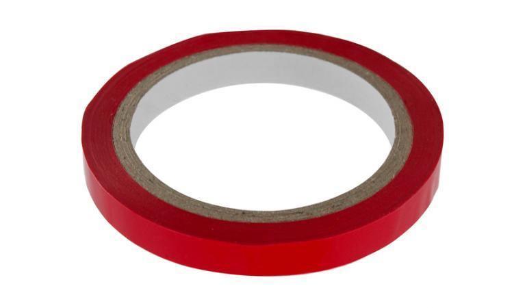 Red adhesive tape roll with white core on plain white background
