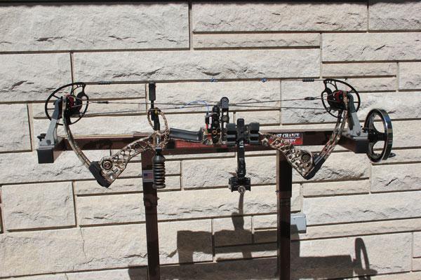 Compound bow on tuning stand against stone wall, outdoor archery equipment close-up