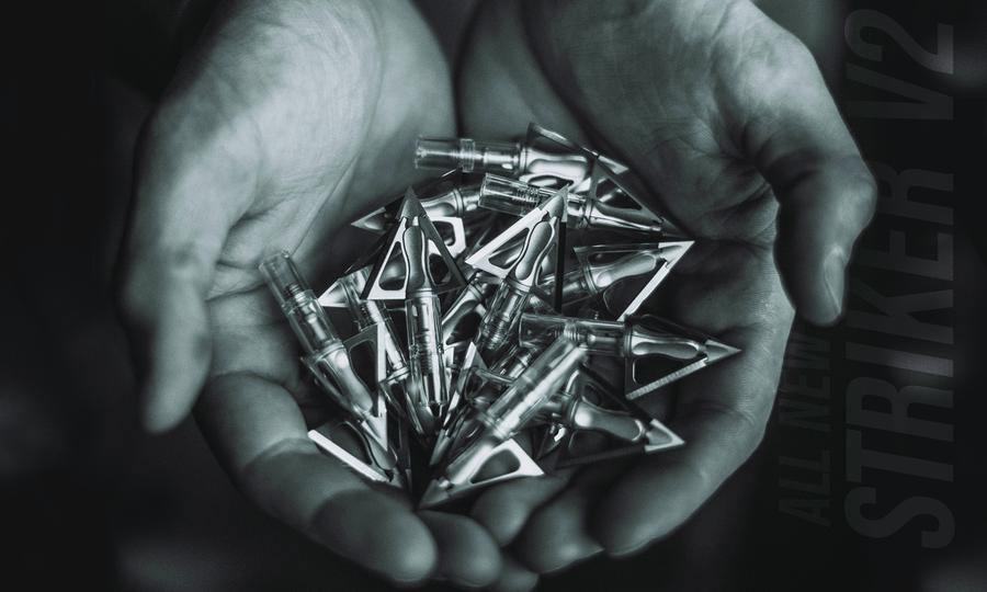 Hands holding several G5 Outdoors Striker V2 archery broadheads, metallic blades visible.