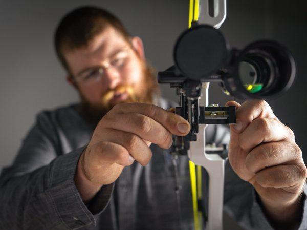 Man adjusting Hamskea Gen2Pro third axis level on compound bow for archery setup