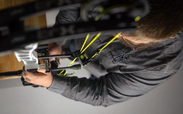 Man using Hamskea Gen2Pro third axis level on compound bow indoors