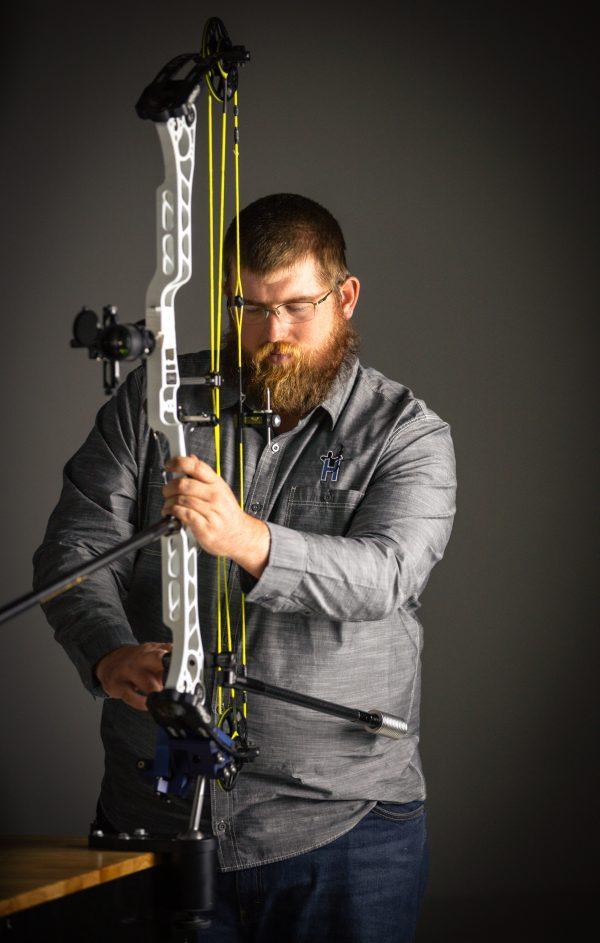 Man adjusting Hamskea Archery Gen2Pro third axis level on compound bow indoors