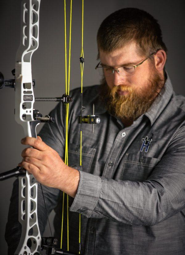 Man adjusting compound bow with Hamskea Archery GEN2PRO third axis level indoors