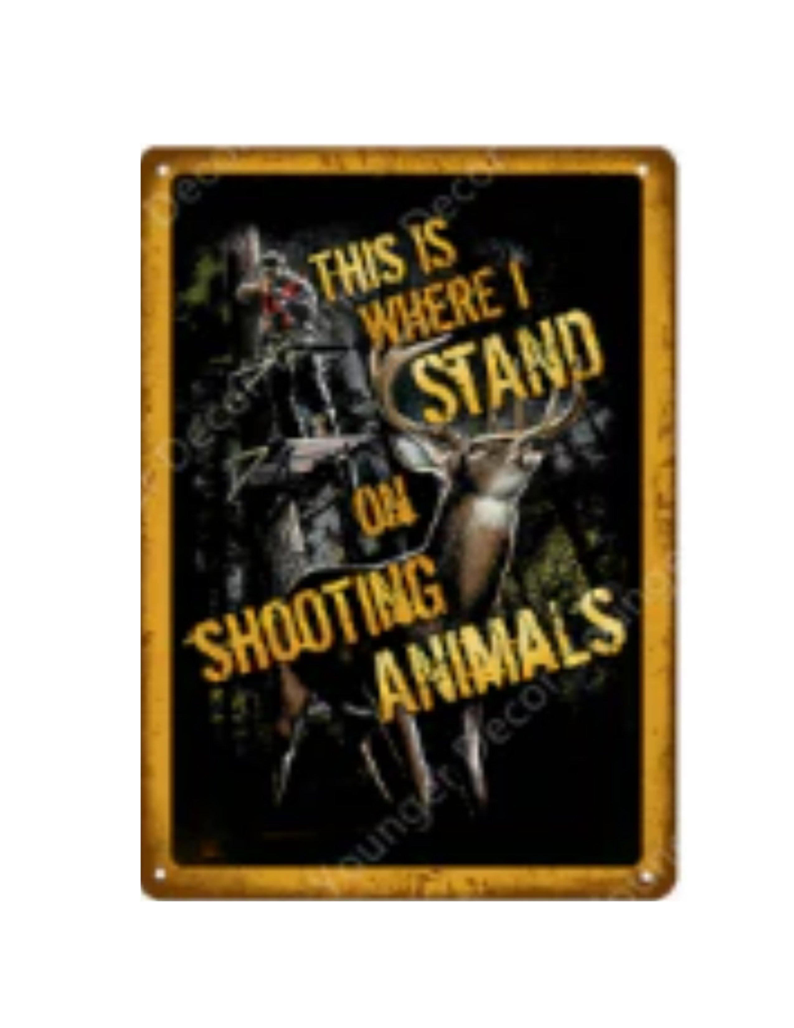 Metal tin sign with 'This is where I stand on shooting animals' text, deer, and hunter illustration