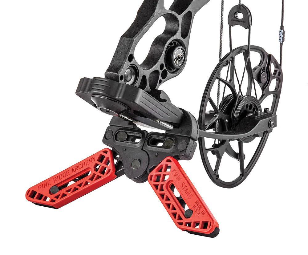 Pine Ridge Archery Kwik Stand bow support with red legs attached to a black compound bow.