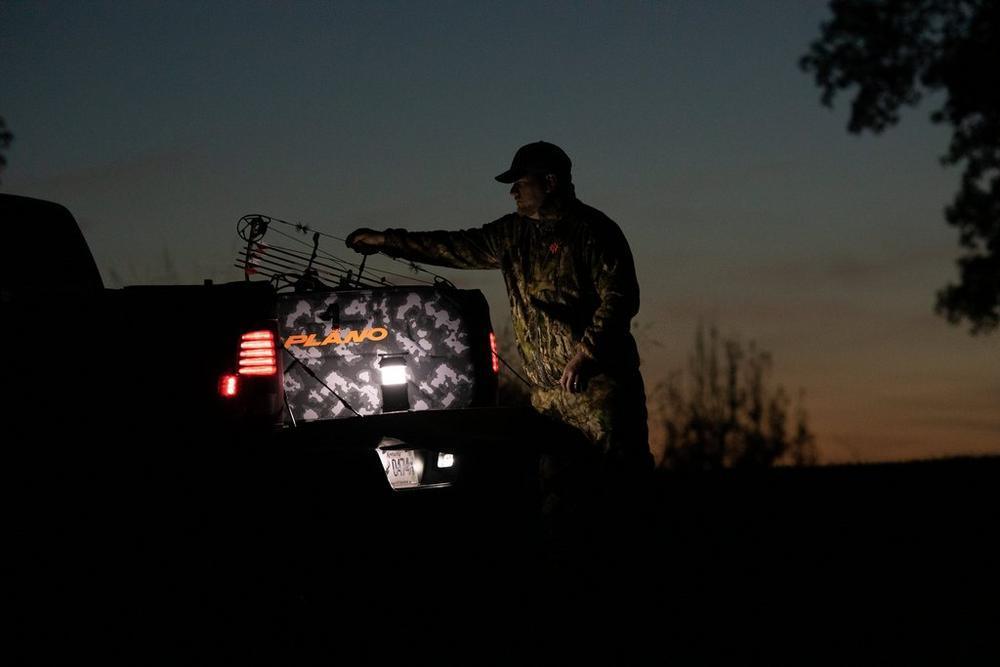 Hunter loading Plano Archery Stealth Bow Case into truck at dusk outdoors