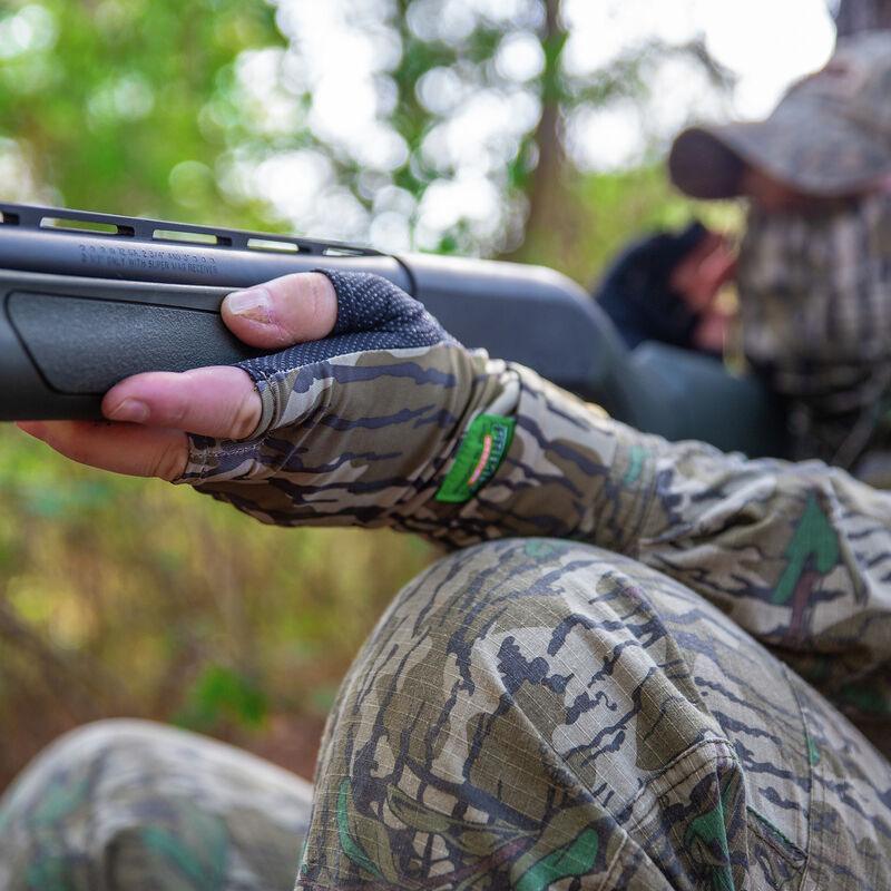 Hunter wearing Primos fingerless camo gloves holding rifle outdoors in forest setting