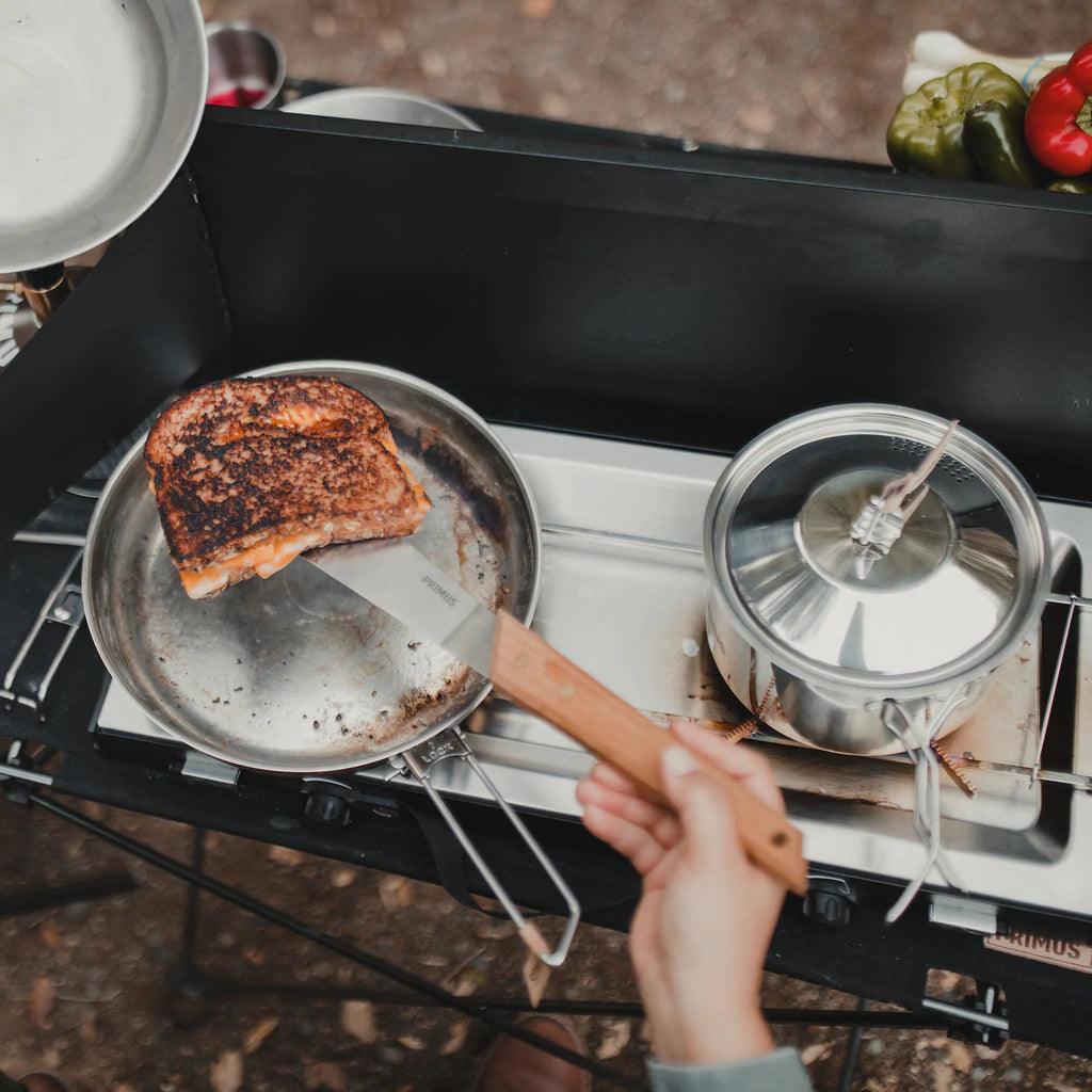 Primus Alika stove cooking grilled cheese sandwich outdoors with pot and vegetables