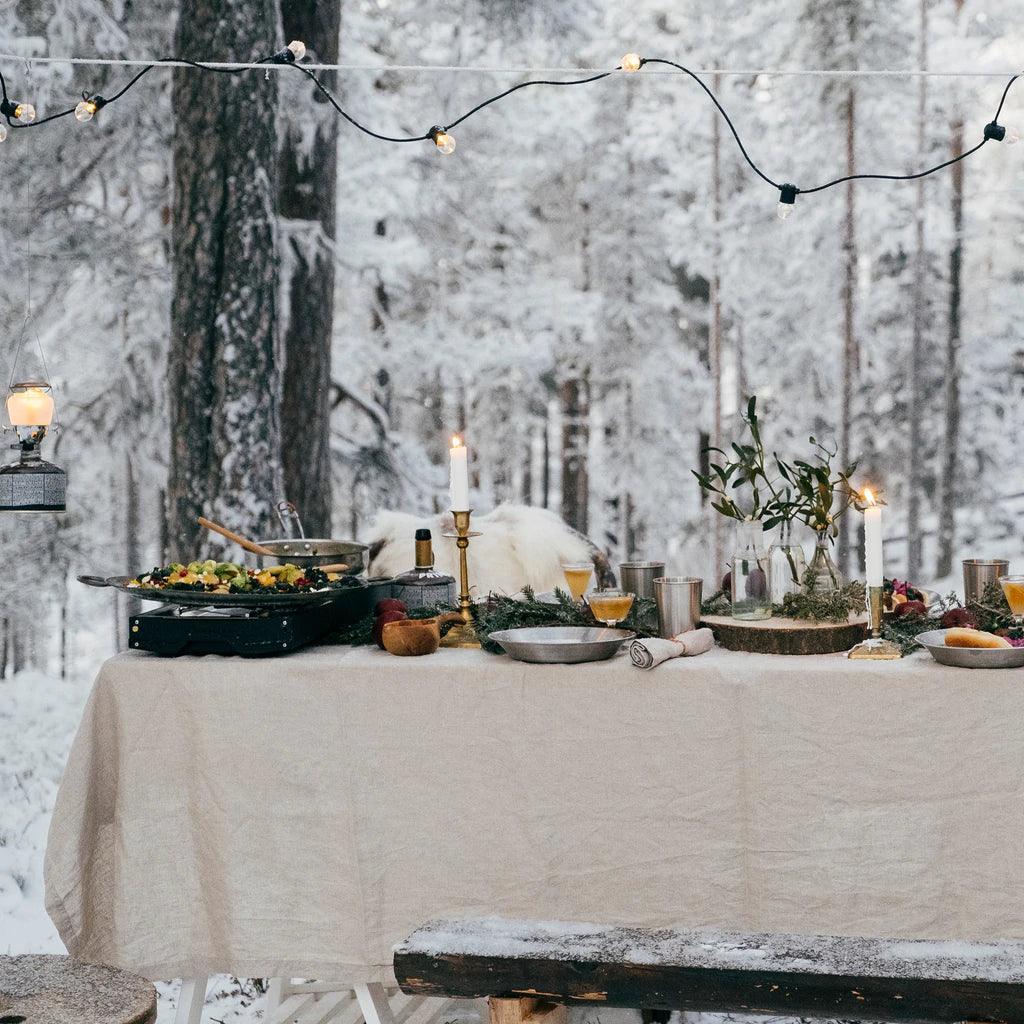 Primus Alika camp stove on winter outdoor table set for a meal in snowy forest setting