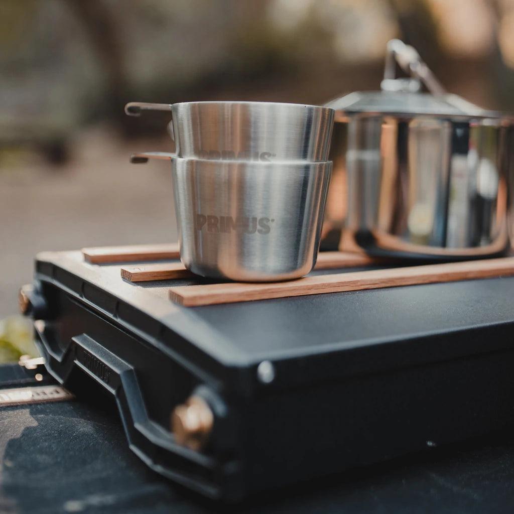 Primus Alika stove with stainless steel camping mugs and pot outdoors