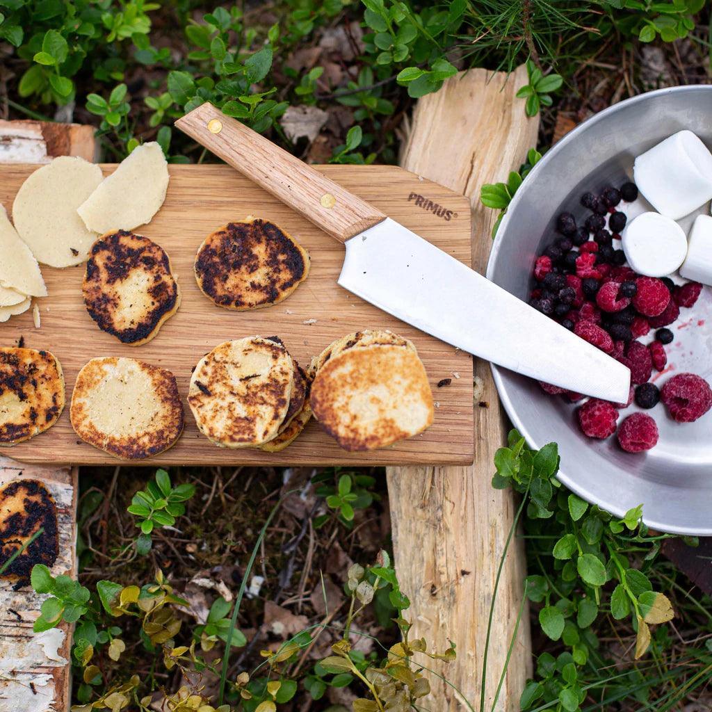 Primus campfire cutting set with knife, wooden board, pancakes, marshmallows, and berries outdoors