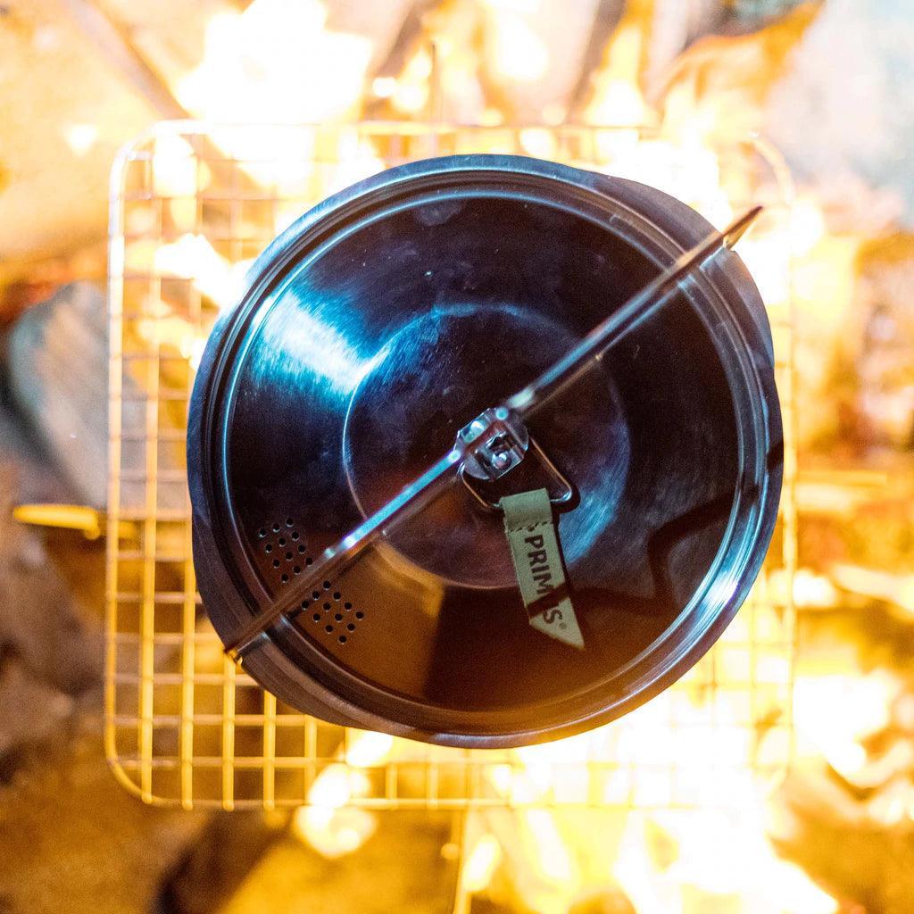 Primus stainless steel campfire pot on grill over open flame outdoors