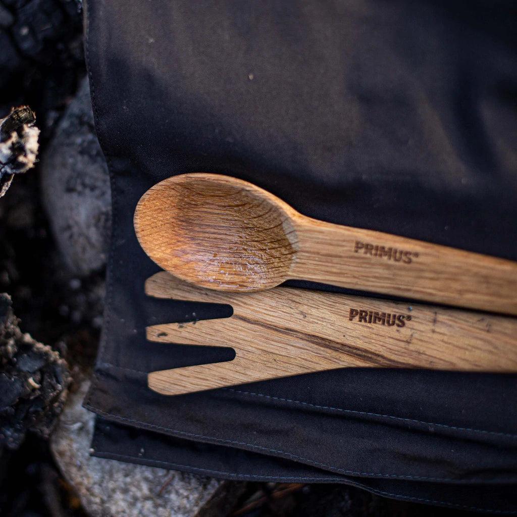Primus wooden camping spoon and fork set on black fabric outdoors