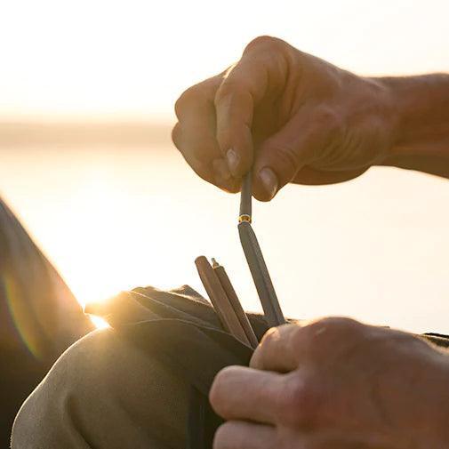 Person assembling Primus campsite chopsticks outdoors at sunset