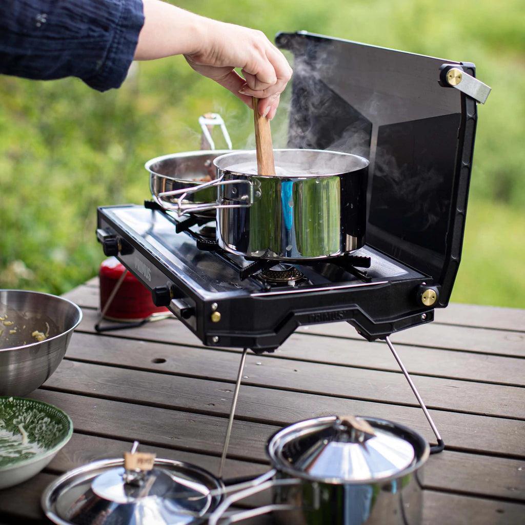 Person cooking with Primus campsite cookset on portable camping stove outdoors