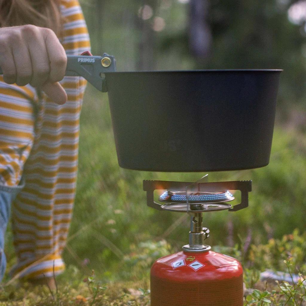 Primus campsite pot gripper holding black pot on portable camping stove outdoors