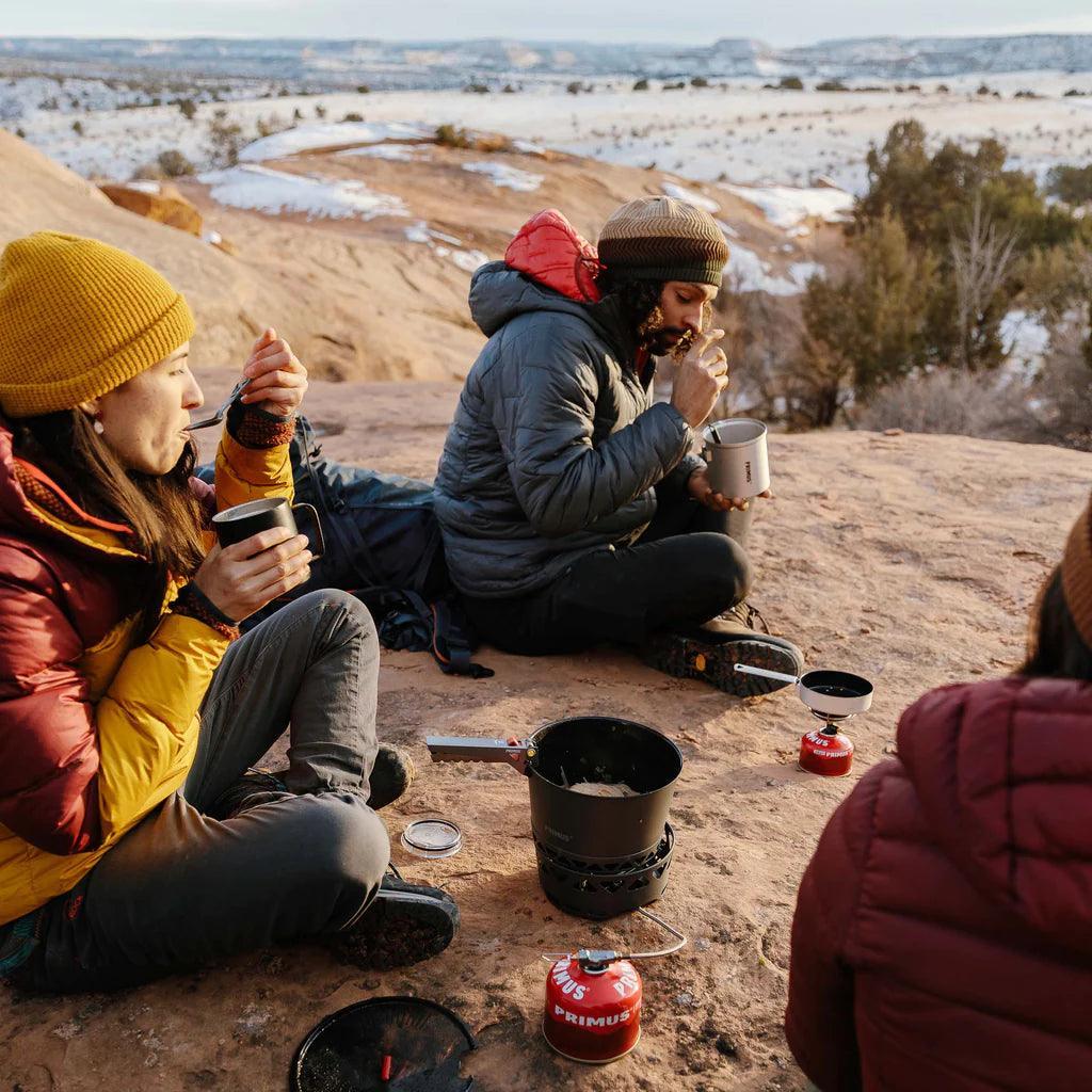 Campers eating with Primus Crimp Pot Gripper stove on rocky outdoor landscape