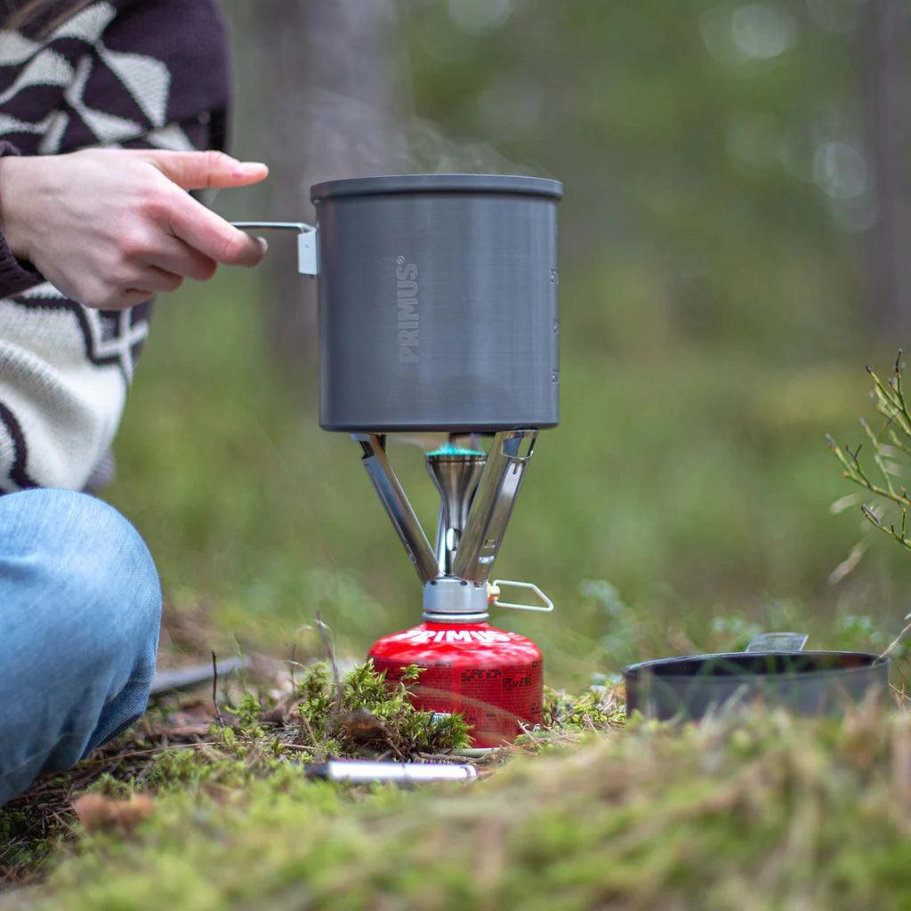 Primus Firestick backpacking stove heating pot outdoors in forest setting