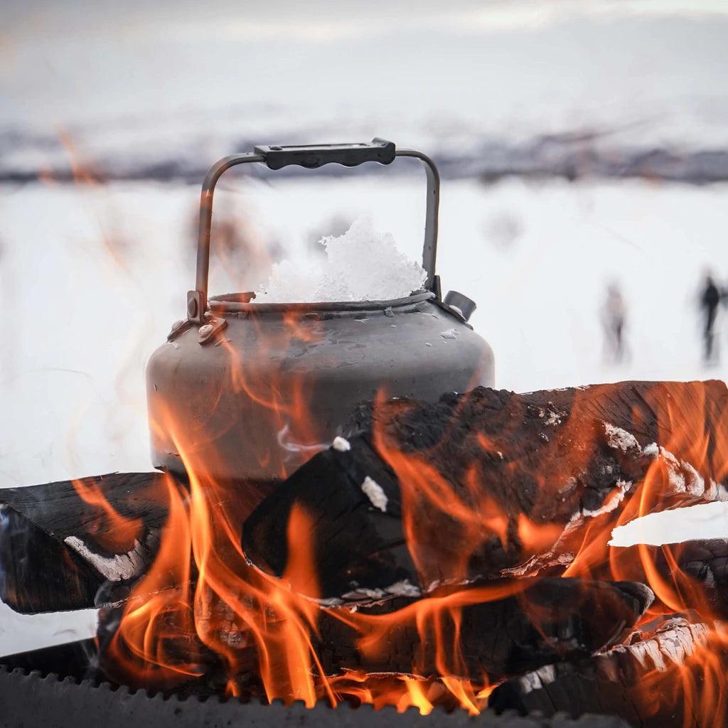 Primus Litech camping kettle melting snow on campfire in snowy outdoor setting