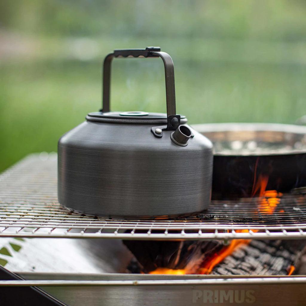 Primus Litech camping kettle on outdoor grill over campfire, stainless steel, outdoors