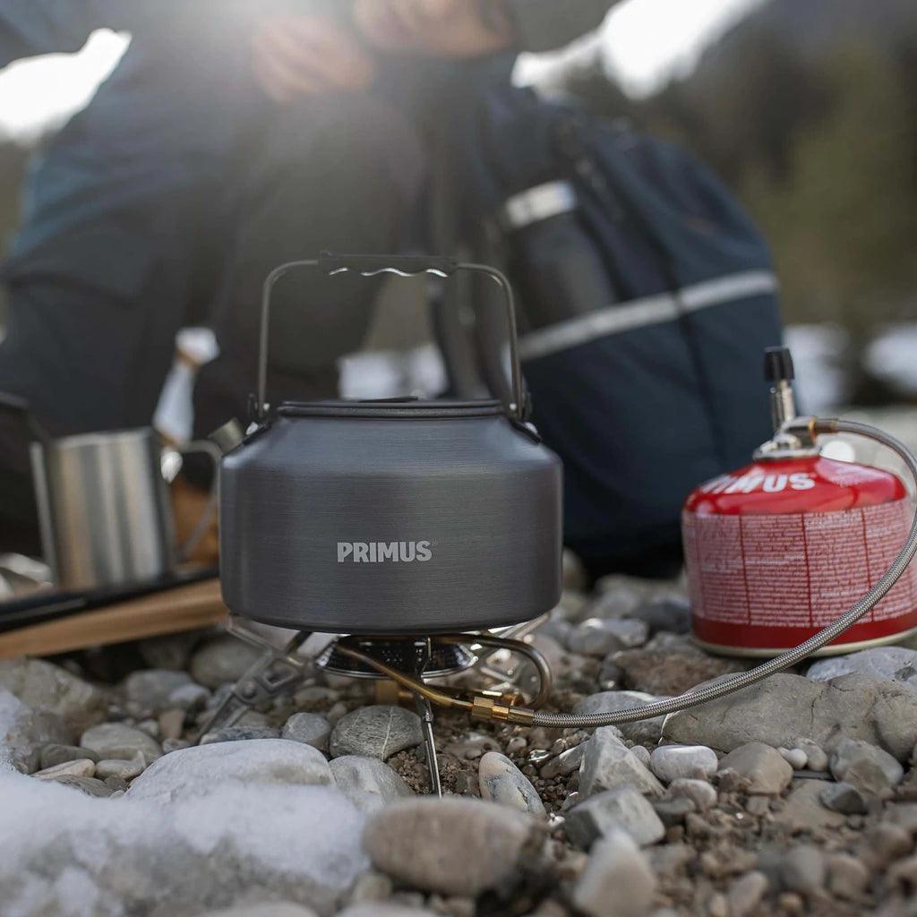 Primus Litech camping kettle on portable stove with gas canister outdoors on rocky ground