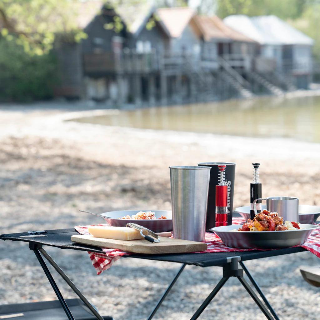 Primus campsite salt and pepper mills on outdoor picnic table with food and lake view