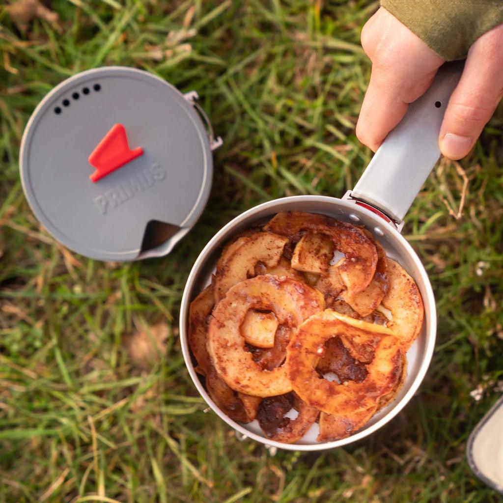 Primus Essential Trek pot with cooked food outdoors on grass, camping cookware