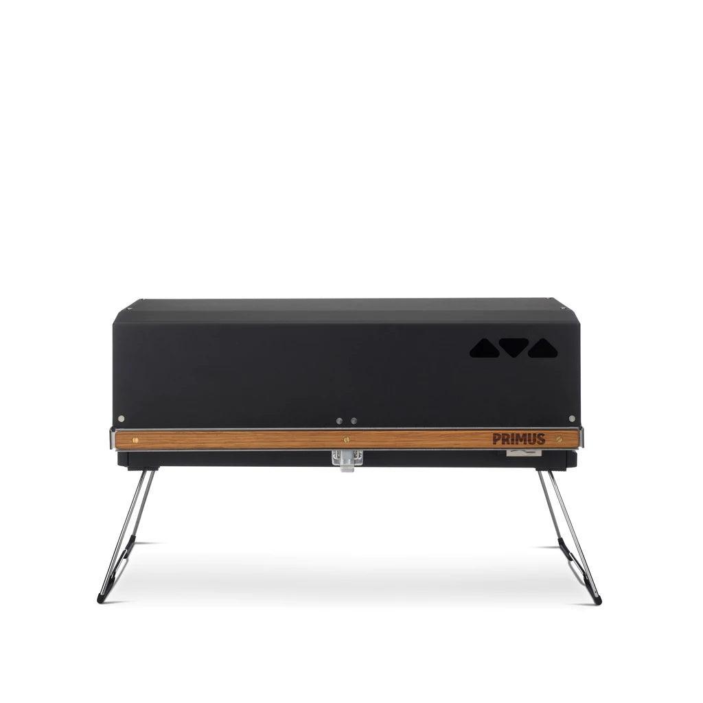 Primus Kuchoma portable gas camp grill with black lid and wooden trim on foldable legs