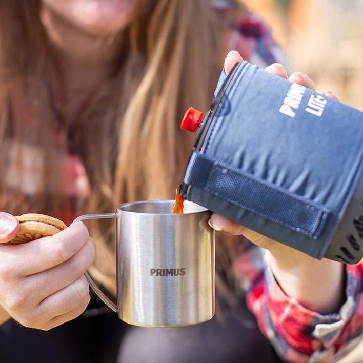 Pouring coffee from Primus Lite Plus stove into Primus stainless mug outdoors