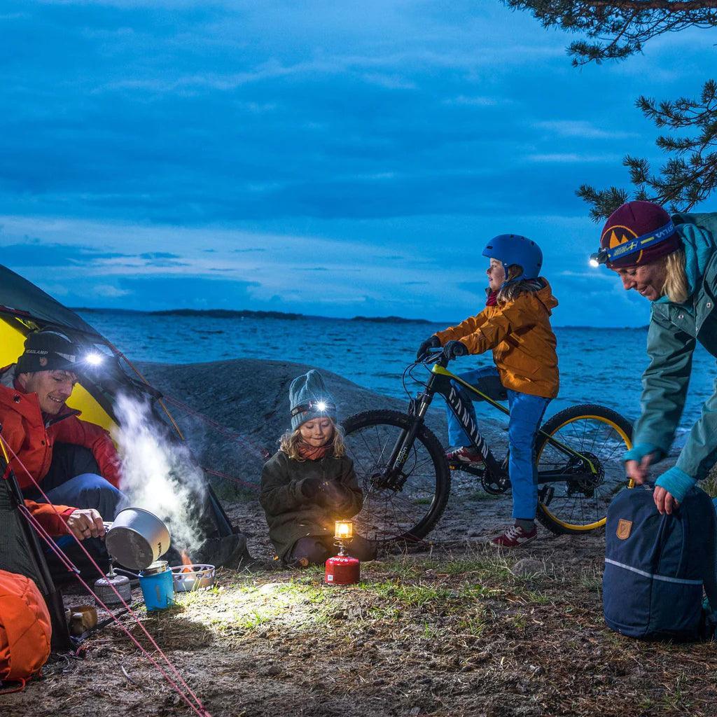 Family camping by lake with Primus Micron lantern, tent, and mountain bike at dusk