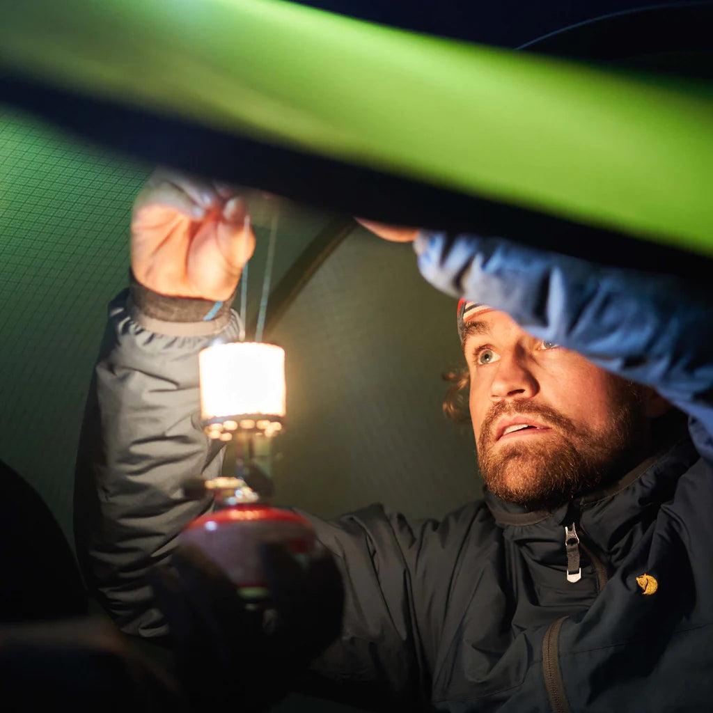Man lighting Primus Micron camping lantern with steel mesh inside a tent