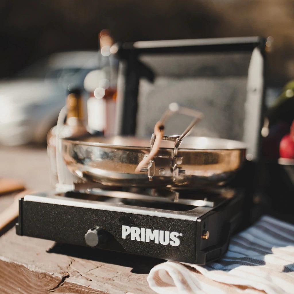 Primus Moja single burner camp stove with metal pan on wooden outdoor table