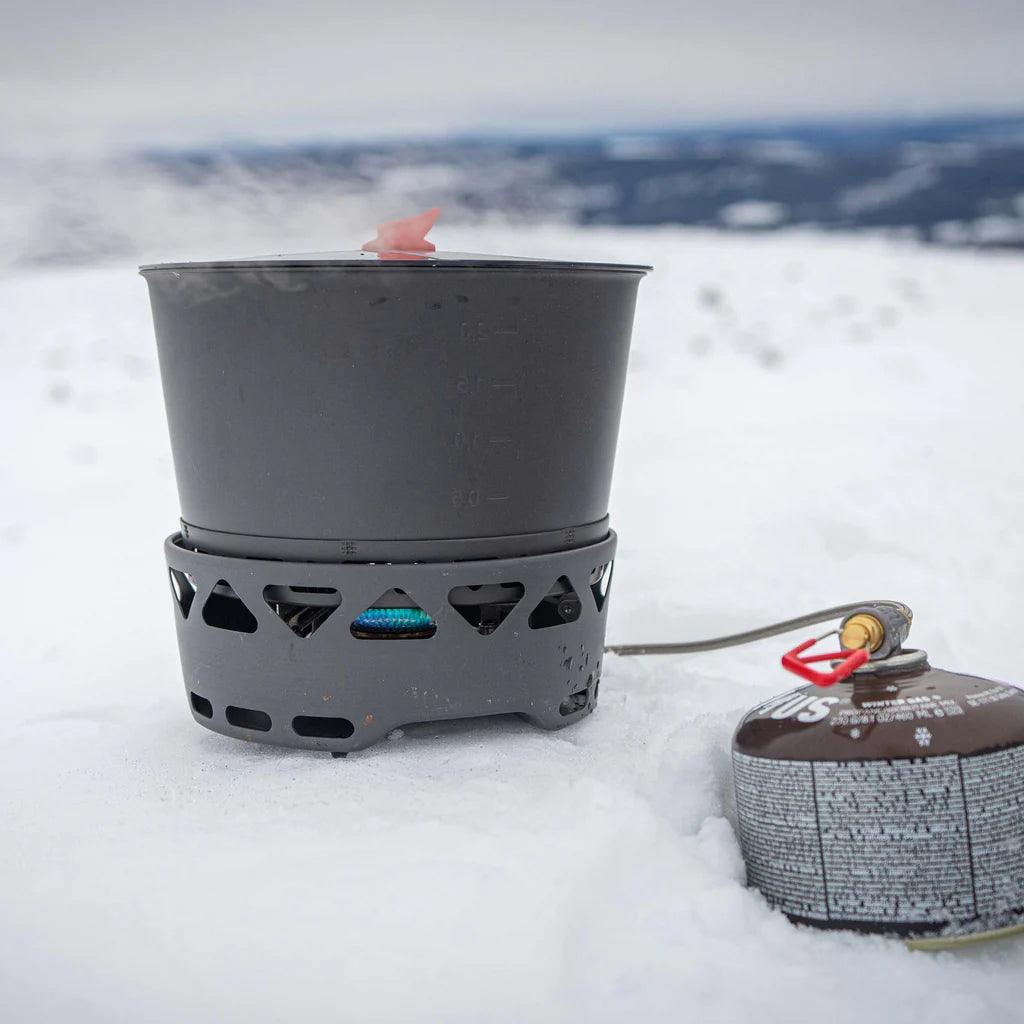 Primus PrimeTech stove system in use on snowy outdoor terrain with gas canister