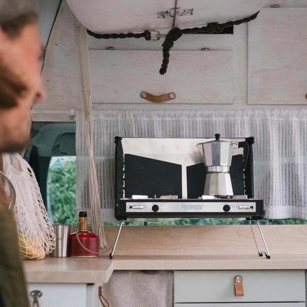 Primus Tupike camp stove with moka pot on van kitchen counter, camping gear visible